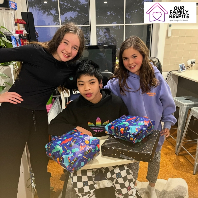 Warm indoor scene of three kids with presents, representing the comfort and support of overnight respite care.