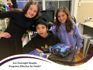 Child supported by respite programs for youth sitting with smiling friends and wrapped birthday gifts on a kitchen table