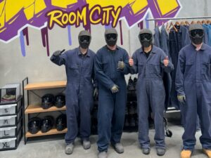 Four men in protective gear posing at an indoor facility, ready for hands-on respite care activities promoting teamwork and confidence