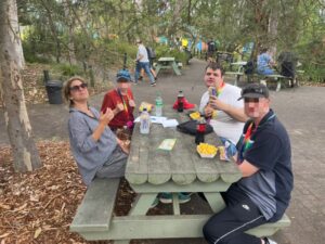 Group enjoying lunch at a park during outdoor respite care activities, encouraging social interaction and community participation