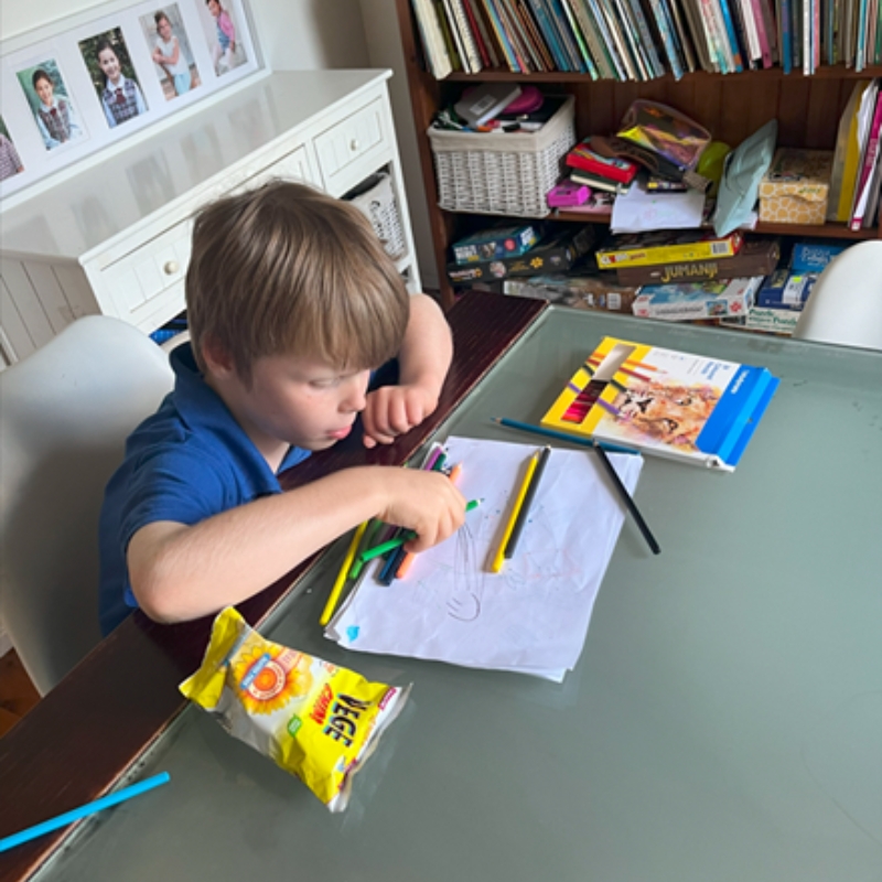Child drawing with coloured pencils at home desk, representing creative activities offered in NDIS Respite Accommodation.