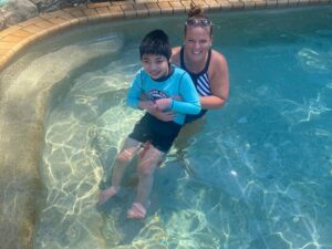Child with disability enjoys pool time with carer, showing active types of respite care in a supportive setting.
