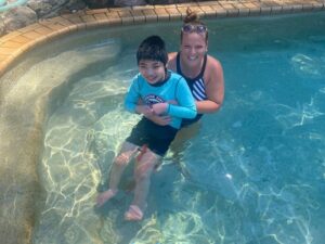 Support worker helping a child with disability enjoy pool time during ndis respite in a safe outdoor setting.