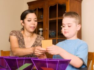 A support worker helps a young boy with an activity at home, providing caring and structured respite children support.