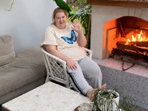 Woman waving beside a fireplace with a parrot on her head, illustrating respite care privacy rights.
